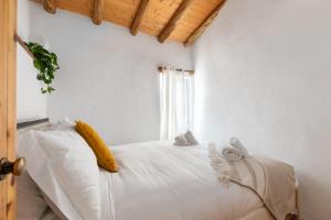 a bedroom with a bed with white sheets and yellow pillows at Da Casa Sesta in Sagres