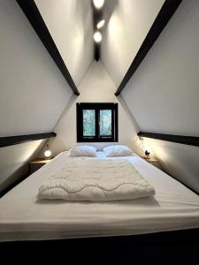 a large white bed in a room with a window at Chaleureux chalet à Durbuy in Durbuy