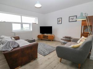Una sala de estar con dos sofás y un televisor. en Cysgod Y Capel, en Benllech