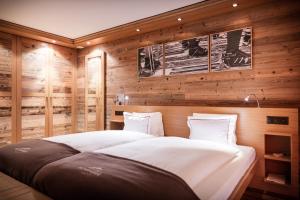 a bedroom with a large bed with wooden walls at Petit Chalet by Sch&ouml;negg in Zermatt