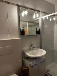 a white bathroom with a sink and a mirror at Appartement Les Salines in Roche