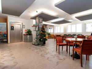 ein Weihnachtsbaum in einem Restaurant mit Tischen und Stühlen in der Unterkunft Hotel Pere D'Urg 3000 in Encamp
