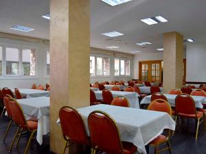 um quarto com mesas e cadeiras brancas e janelas em Hotel Pere D'Urg 3000 em Encamp