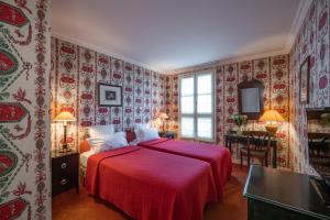 una camera da letto con letto con lenzuola rosse e carta da parati di Hôtel Prince de Conti a Parigi