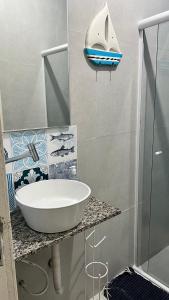 La salle de bains est pourvue d'un lavabo et d'une douche. dans l'établissement Casa de Praia com piscina, à Boicucanga