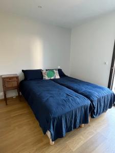 uma cama num quarto com um cobertor azul em Glen Ross, plage à moins de 10 min à pied em Névez