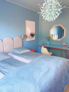 a blue bedroom with two beds and a chandelier at Ihana kaksio Linnanmäen vieressä in Helsinki