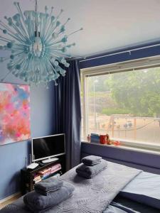 a bedroom with a bed and a window and a chandelier at Ihana kaksio Linnanmäen vieressä in Helsinki