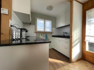 a kitchen with white cabinets and a counter top at Blässchopfhüsli in Nesslau