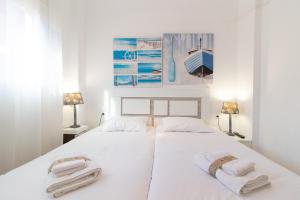プエルト・デ・サグントにあるGlobal Properties, Practico apartamento en Puerto de Sagunto cerca de la playaの白いベッドルーム(ベッドにタオル2枚付)