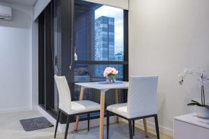 einen Tisch mit zwei Stühlen und eine Vase mit Blumen darauf in der Unterkunft Relaxing 1br1ba Apartment In Melbourne Cbd in Melbourne