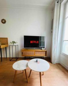 a living room with two tables and a tv at Appartement Quartier Tour Eiffel in Paris