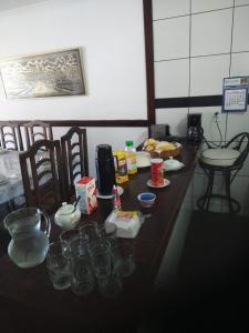 - une longue table en bois avec de la vaisselle et des verres dans l'établissement Casa com piscina e sauna em Petrópolis, à Petrópolis