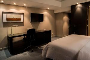 een slaapkamer met een bed, een bureau en een televisie bij Hotel Tamanaco Caracas in Caracas