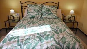 a bed with a green and white comforter and two lamps at Casa rural en San Mateo in Las Palmas de Gran Canaria