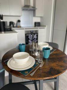 a wooden table with plates and dishes on it at Hemel Apartments- Tranquil Haven in Hemel Hempstead