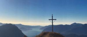 una cruz en la cima de una colina con montañas en Chalet Tre Santelle, en Bossico