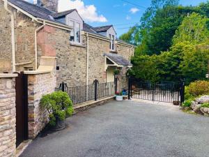 a stone house with a gate and a driveway at Norwood Cottage in Kirkby Lonsdale