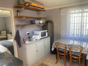 eine Küche mit einem Tisch mit Stühlen und einer Mikrowelle in der Unterkunft Shades of grey in Oudtshoorn