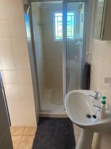 ein weißes Bad mit einer Dusche und einem Waschbecken in der Unterkunft Shades of grey in Oudtshoorn