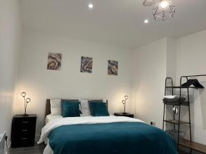 a white bedroom with a bed with blue sheets at Hemel Apartments- Tranquil Haven in Hemel Hempstead