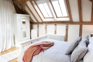 Schlafzimmer mit einem weißen Bett und einem Dachfenster in der Unterkunft Acorn Barn in Crediton