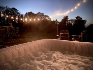 a hot tub in a backyard at night with lights at Acorn Barn in Crediton