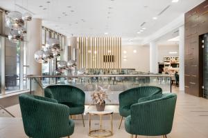 a lobby with green chairs and a glass counter at Corso Hotel Pécs in Pécs