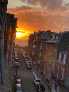 a city street with cars parked in front of a sunset at Grand studio avec petite vue mer in Mers-les-Bains