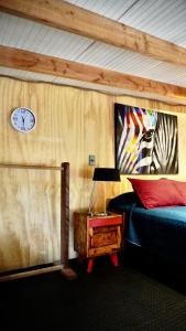 sypialnia z łóżkiem i zegarem na ścianie w obiekcie Molco Cabins Loft w mieście Pucón