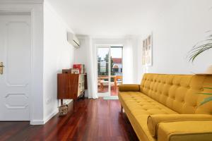 a living room with a yellow couch and wooden floors at Casa Verde in Tavira