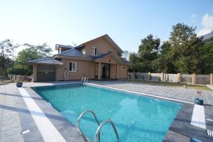 a swimming pool in front of a house at Antaraal Resort & Spa A Village Resort in Dharamshala