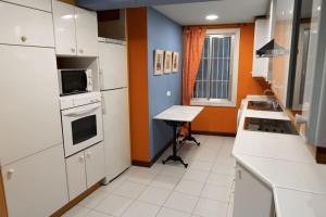 een keuken met witte apparatuur en een oranje en blauwe muur bij Casa Grande en Casco Histórico in Santander