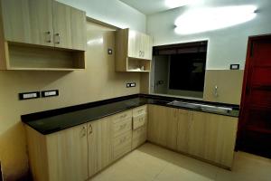 an empty kitchen with wooden cabinets and a television at Alekhya Suites - Panaji in Marmagao