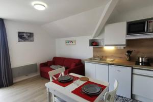 een keuken en een woonkamer met een rode bank bij Studio 2 pers avec accès piscine et sauna in Les Déserts
