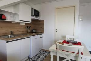 cocina con armarios blancos, fregadero y mesa en Studio 2 pers avec accès piscine et sauna en Les Déserts