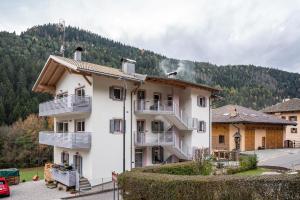 a large white building with balconies and a mountain at Martina's Place in Castello di Fiemme