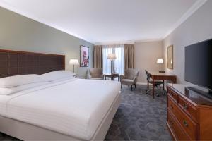 ウィンザーにあるDelta Hotels by Marriott Heathrow Windsorのベッド1台、薄型テレビが備わるホテルルームです。