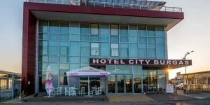 a hotel building with tables and chairs in front of it at Hotel City in Burgas City