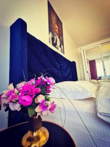 een vaas met bloemen op een tafel naast een bed bij Studio Alexandra in Galaţi