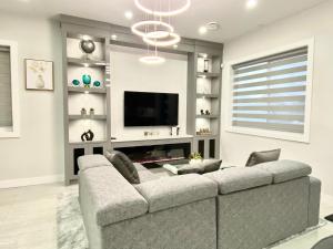 Modern and New house near PNE في فانكوفر: غرفة معيشة مع أريكة كبيرة وتلفزيون بشاشة مسطحة