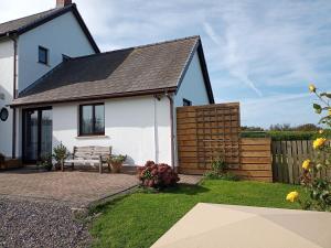 una casa blanca con un banco en el patio en Cowslip Corner Room with Sea View en Broad Haven