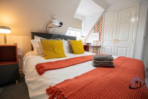 ein Schlafzimmer mit einem Bett mit gelben und orangefarbenen Kissen in der Unterkunft Garfield House, allocated parking, free wi-fi, pets, corporates welcome in Wellingborough