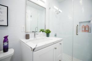 a white bathroom with a sink and a shower at Stylish 4BR Home near Disneyland wParking in Midway City