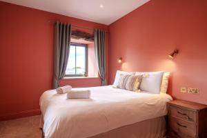 a bedroom with a large bed with red walls at Tan Apartment - Shap - Great for Walkers in Shap