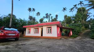a small house with a red car parked next to it at Rose villa in Meenangadi