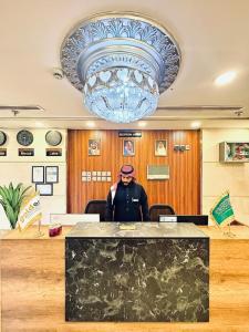 a man standing in an office under a large chandelier at فندق جولدن العزيزية in Makkah