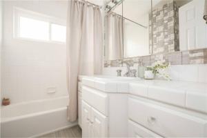 Baño blanco con 2 lavabos, bañera y espejo en Tranquil 4BR Home in Whittier, en Whittier