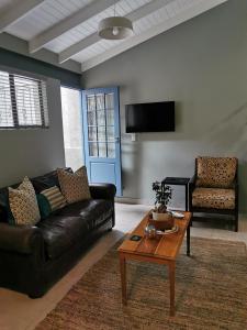 een woonkamer met een zwarte leren bank en een tafel bij The Blue Door in Pretoria