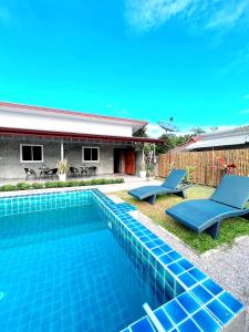 a swimming pool with two blue chairs next to a house at PP Pool Villa Maesalong Chiangrai in Mae Salong Nai